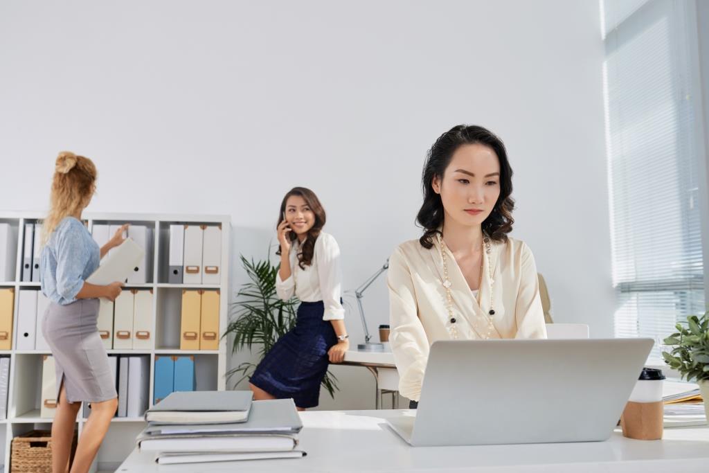 Pretty Chinese business lady working on laptop in office